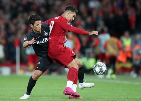 Hwang Hee-chan berebut bola dengan Roberto Firmino. (c) AP Photo