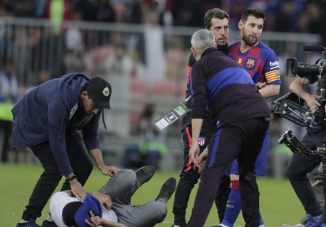 Momen ketika petugas keamanan menangkap fans yang menyergap Lionel Messi dari belakang. (c) AP Photo