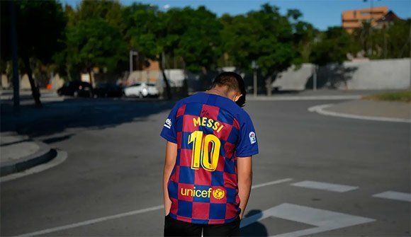 Seorang bocah tertunduk lesu saat menunggu Lionel Messi di lokasi latihan Barcelona, Senin (31/8/2020). Messi secara mengejutkan tidak datang untuk mengikuti tes swab Covid19 yang dijadwalkan Barcelona. (c) AFP/Paul Barrena