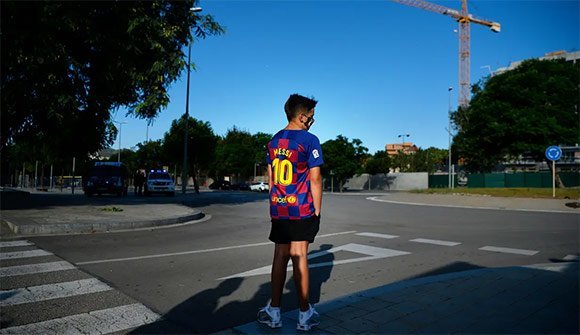 Seorang bocah tertunduk lesu saat menunggu Lionel Messi di lokasi latihan Barcelona, Senin (31/8/2020). (c) AFP/Paul Barrena