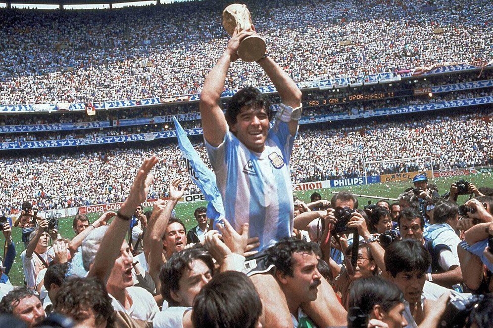 Diego Maradona dengan trofi Piala Dunia 1986 usai mengalahkan Jerman Barat di Final. (c) AP Photo