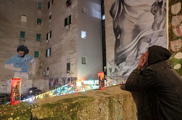 Fans Napoli tampak bersedih dan memandangi mural Maradona yang terpajang gagah di Naples. (c) AP Photo
