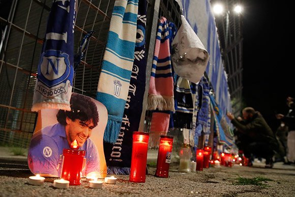 Fans Napoli meletakkan pernak-pernik Maradona di luar stadion San Paolo yang rencana akan berganti nama sebagai tribut untuk mendiang Maradona. (c) AP Photo