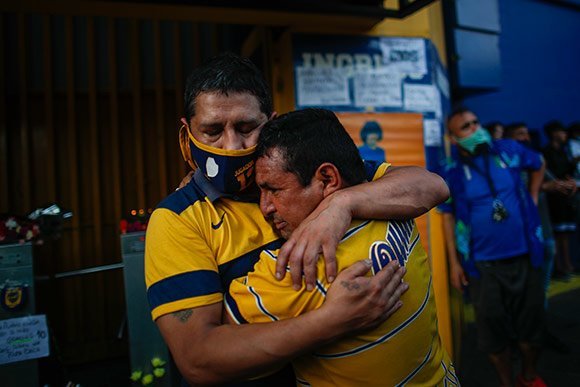 Dua suporter saling berpelukan setelah Maradona dinyatakan meninggal dunia akibat serangan jantung. (c) AP Photo