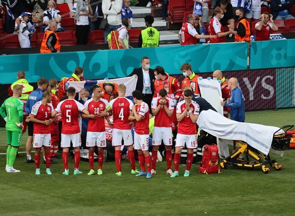 Pemain Denmark membentuk barisan untuk menutupi aktivitas tim medis. (c) AP Photo