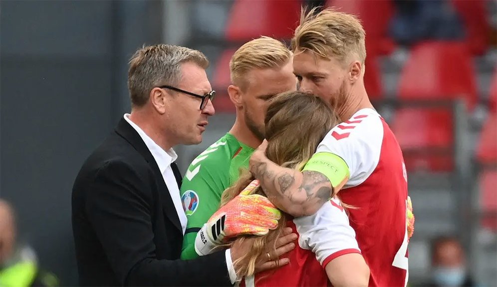 Bersama kiper Denmark, Kasper Schmeichel, kapten tim Simon Kjaer menecoba menenangkan Sabrina Kvist Jensen, istri Christian Eriksen. (c) AFP/Jonathan Nackstrand