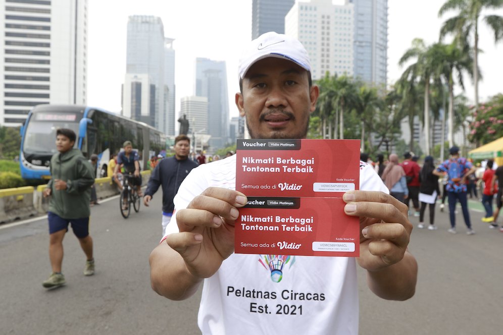 Seorang warga menunjukkan hadian voucher nonton Piala Dunia 2022 di Vidio saat Car Free Day (CFD) di kawasan Sudirman, Jakarta, Minggu (06/11/2022). (c) Bola.net/M iqbal Ichsan