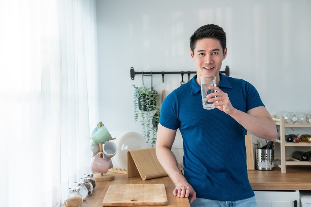 Seorang pria mengonsumsi air putih. (c) Shutterstock