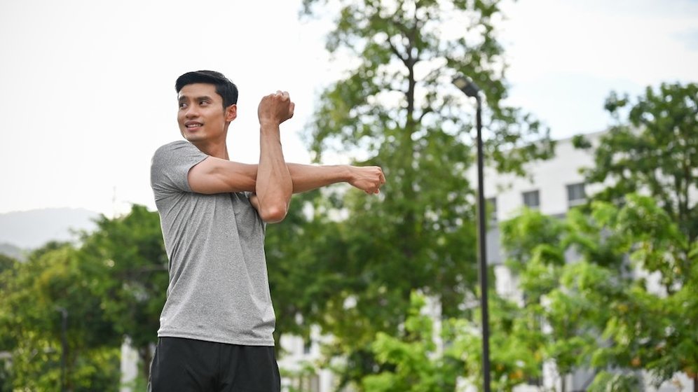 Seorang pria melakukan pemanasan sebelum berolahraga. (c) Shutterstock
