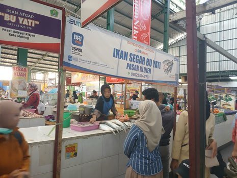 Suasana di Pasar Klojen pada acara Festival Jajanan Pasar. Seorang pedangan ikan memakai spanduk dari BRI (c) Asad Arifin