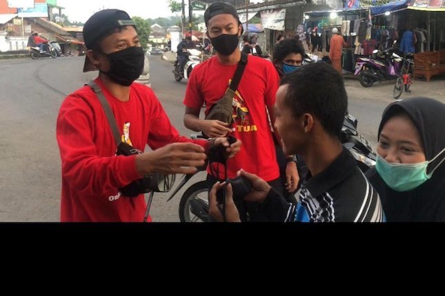 Pemain Persikabo, Gustur Cahyo, membagikan masker di Magelang (c) Bola.com/Permana Kusumadijaya