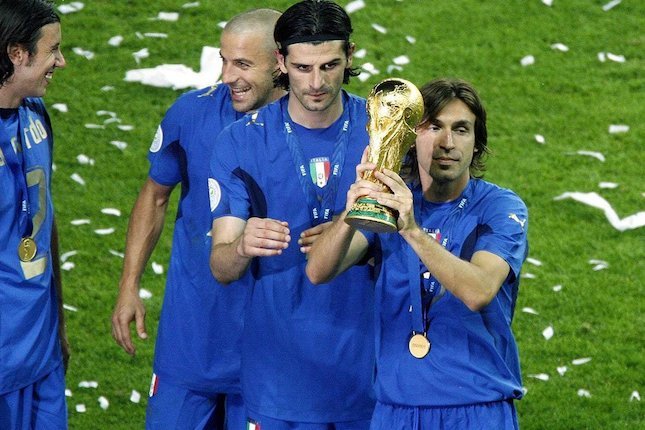 Andrea Pirlo (kanan) mengangkat trofi Piala Dunia 2022 (c) FIFA
