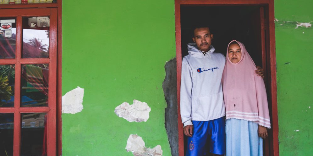 Warga Tumpang, Kabupaten Malang, Lutifiati (kanan) dan putranya Rizal Putra Pratama, di kediaman mereka, Minggu (9/10/2022). Lutifiati kehilangan suami, Muhammad Arifin, dan putranya, Muhammad Rifki Aditya, yang meninggal pada tragedi di Stadion Kanjuruhan, Sabtu 1 Oktober 2022. (c) Bola.net/Bagas Lazuardi