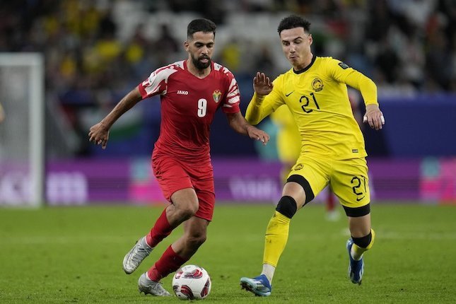 Pemain Malaysia, Dion Cools mencoba menghentikan pergerakan pemain Yordania, Ali Olwan di laga Grup E Piala Asia 2023. (c) AP Photo/Aijaz Rahi