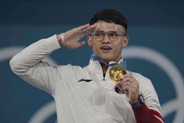 Atlet angkat besi putra Indonesia, Rizki Juniansyah, meraih medali emas kelas 73 kg Olimpiade Paris 2024. (c) AP Photo/Kin Cheung