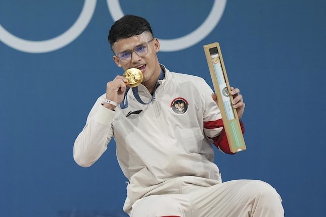 Atlet angkat besi putra Indonesia, Rizki Juniansyah, meraih medali emas kelas 73 kg Olimpiade Paris 2024. (c) AP Photo/Kin Cheung