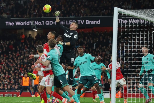 Susunan Pemain Kedua Tim Kiper Wolverhampton, Sam Johnstone mencoba menghalau umpan silang Arsenal, Minggu (14/12/2025) (c) AP Photo/Richard Pelham
