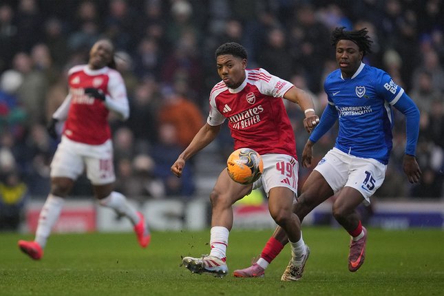 Bek Arsenal, Myles Lewis-Skelly mencoba melepas umpan dalam kawalan pemain Portsmouth, Franco Umeh-Chibueze di laga Piala FA. (c) AP Photo/Kin Cheung