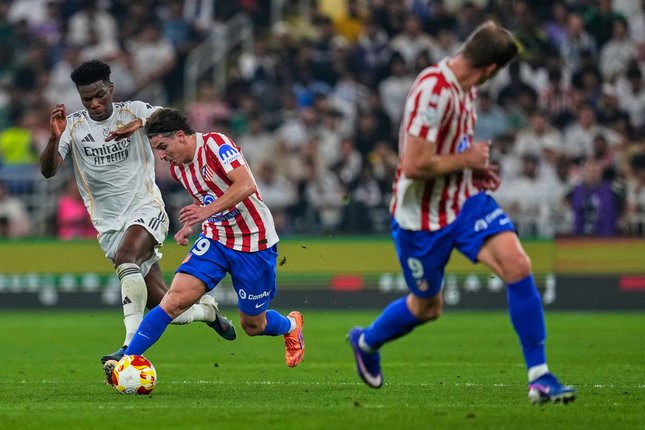 Julian Alvarez dipepet Aurelian Tchouameni di laga Atletico Madrid vs Real Madrid, Jumat (09/01/2026). (c) AP Photo/Altaf Qadri