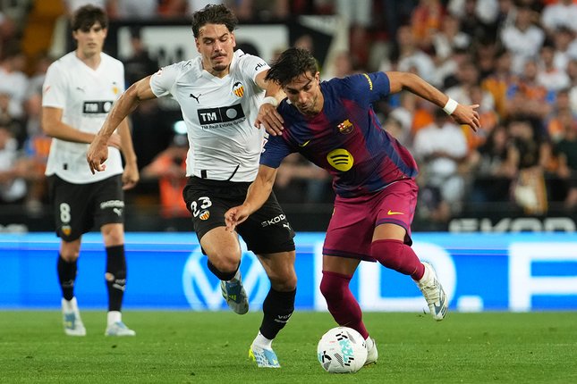 Babak Pertama Filip Ugrinic menghadang Ferran Torres dalam laga Liga Spanyol antara Valencia vs Barcelona di Mestalla, 24 Mei 2026 (c) AP Photo/Alberto Saiz