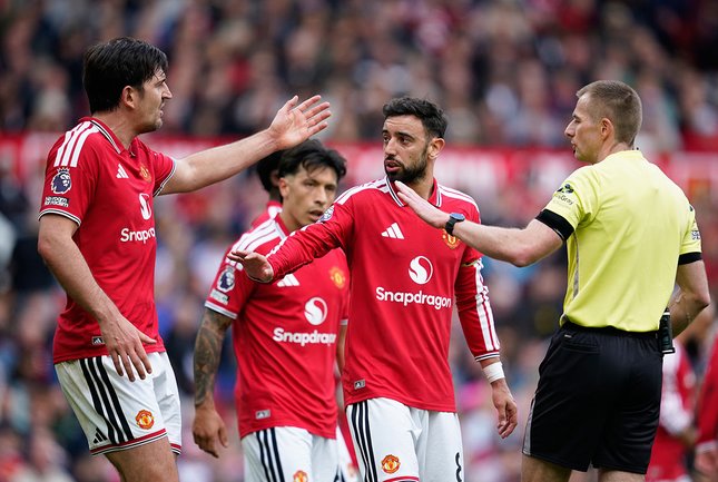 Kiper dan Bek Pemain Manchester United, Harry Maguire (kiri) dan Bruno Fernandes beradu argumen dengan wasit Michael Salisbury. (c) AP Photo/Dave Thompson