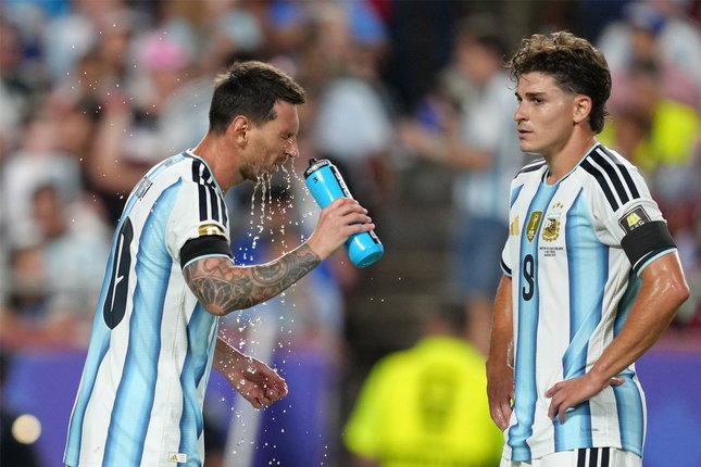 Pemain Argentina Lionel Messi (kiri) membasuh muka dengan air saat rekan setimnya Julian Alvarez melihat ke arahnya dalam laga perempat final Piala Dunia 2026 antara Argentina vs Swiss di Kansas City, Missouri, Sabtu, 11 Juli 2026 (c) AP Photo/Ed Zurga