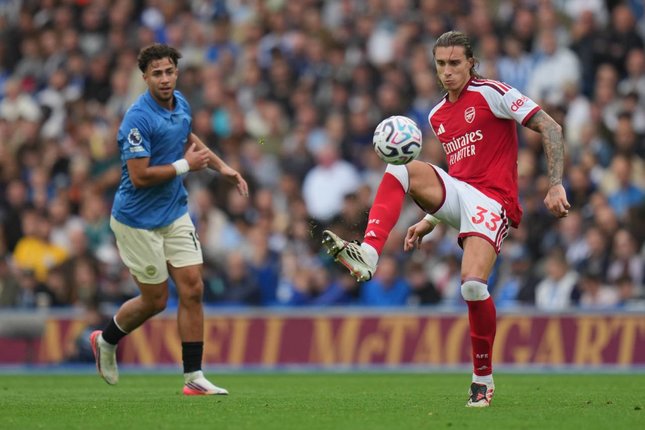 3. Arsenal Justru Kebobolan dari Bola Mati Pemain Arsenal Riccardo Calafiori mengoper bola dalam pertandingan Premier League melawan Brighton & Hove Albion, Sabtu (19/9/2026). (c) AP Photo/Kin Cheung