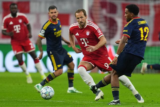 Pemain Arsenal, Jurrien Timber, mengoper bola di depan pemain Bayern, Harry Kane, dalam pertandingan Liga Champions, Kamis (22/10/2026). (c) AP Photo/Martin Meissner