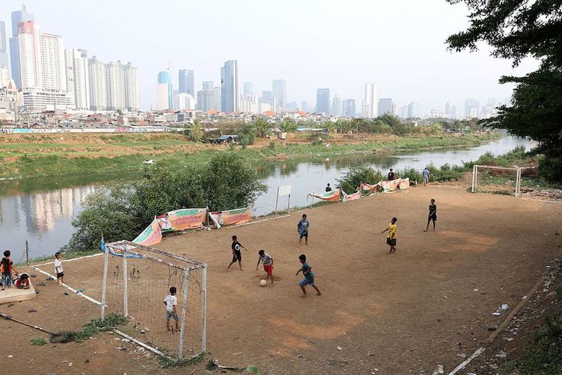 Potret Anak-anak Ibu Kota Bermain Sepak Bola di Pinggir Kali