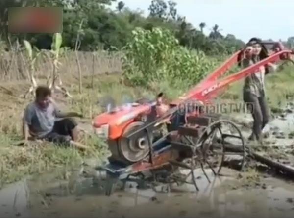 Berusaha mengendalikan traktor pembajak sawah.