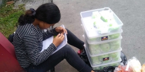 Viral, Gadis Penjual Bakpao Kerjakan PR di Pinggir Jalan