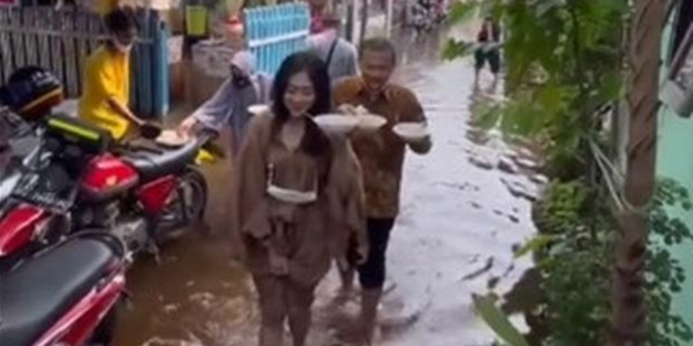 Demi Perut, Tamu Kondangan Terobos Genangan Banjir Demi Ambil Makanan