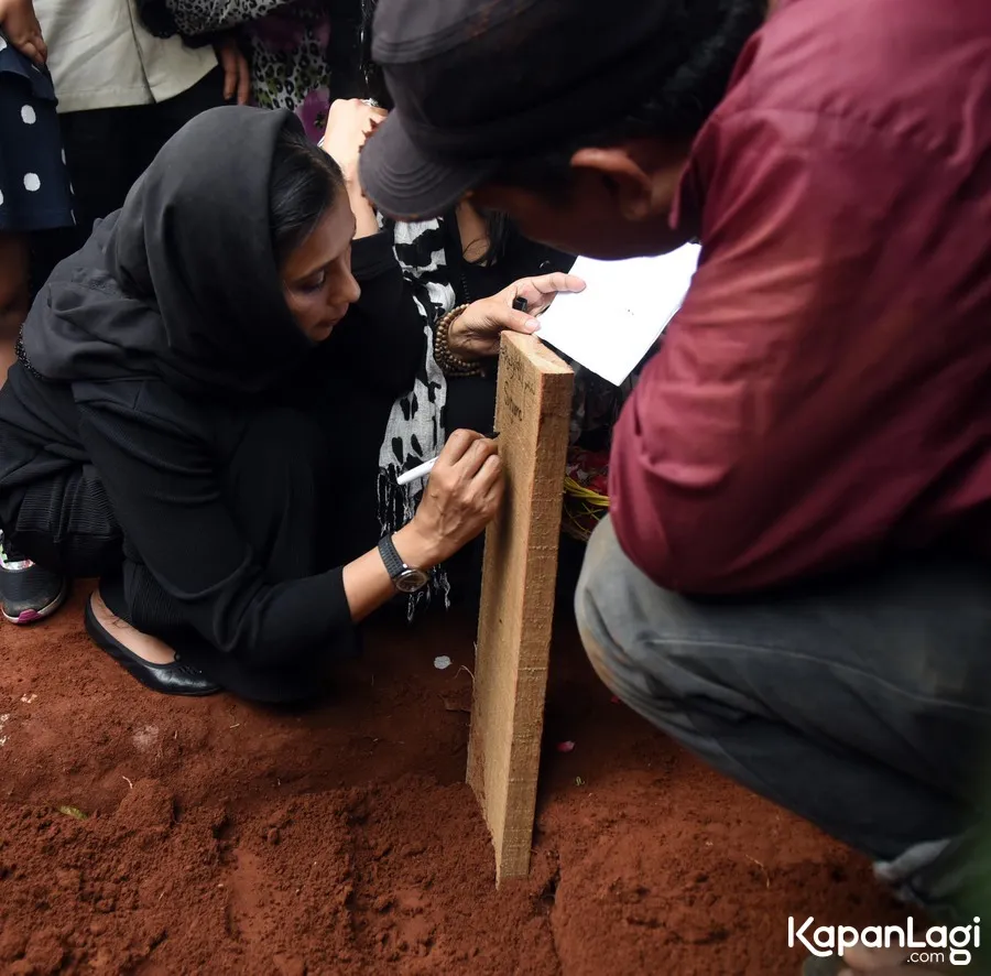 Ayu tuliskan nama Yana di papan nisan © KapanLagi.com®/Akrom Sukarya