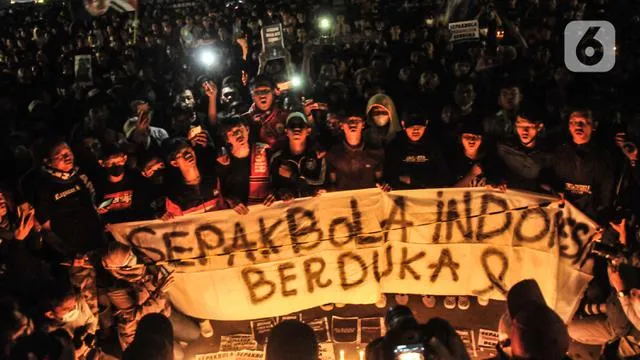 Massa yang tergabung dalam Ultras Garuda Jakarta mengikuti aksi menyalakan lilin dan tabur bunga untuk korban kerusuhan Stadion Kanjuruhan Malang di depan Stadion Gelora Bung Karno (GBK), Jakarta, Min