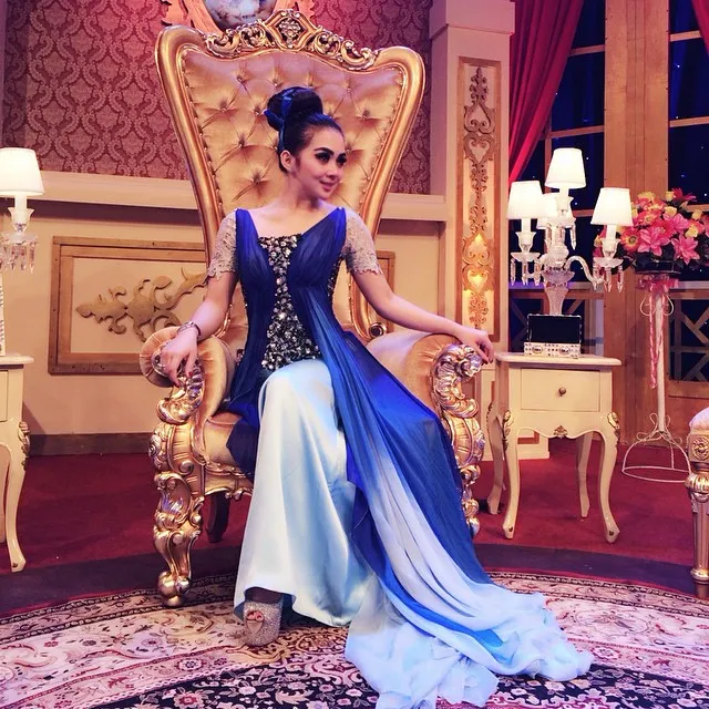 Syahrini kenakan sebuah dress biru megah saat duduk di singgasananya. / Syahrini Official Instagram