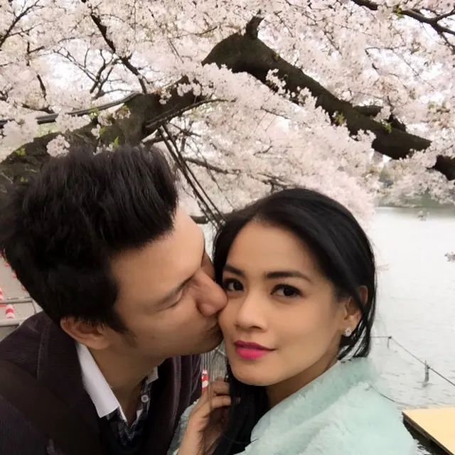 Tian mengecup pipi Titi Kamal di bawah sakura yang sedang bersemi. Romantis banget! © instagram.com/titi_kamall