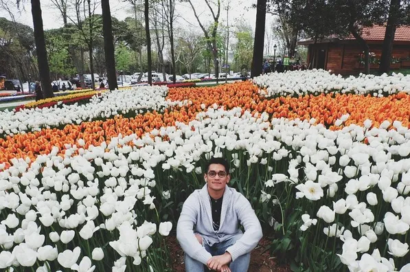 Nikmati liburan, Afgan pamer senyuman manis saat berpose di taman bunga tulip yang indah. /©instagram.com/afgansyah.reza