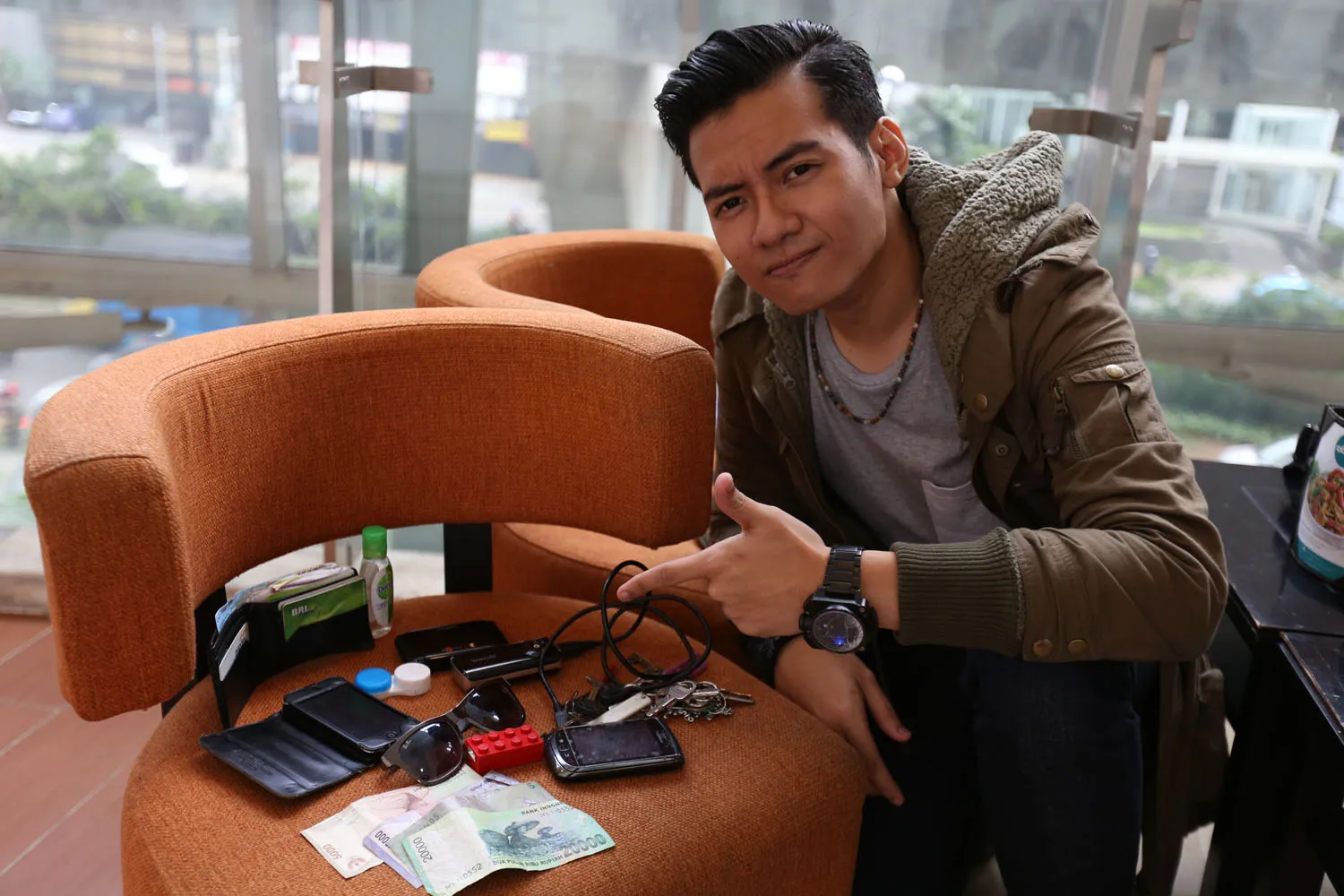 Andre memamerkan isi tasnya. Uang cash, smartphone dan tentunya powerbank! foto: Budy Susanto