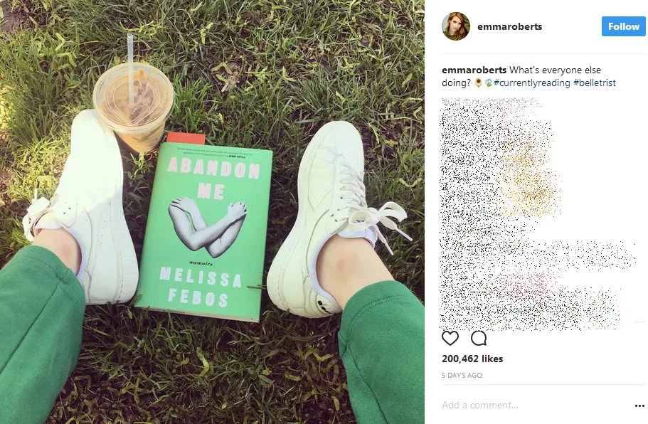 Duduk di atas rumput, Emma Roberts membaca buku ditemani segelas kopi dingin. /©instagram.com/emmaroberts