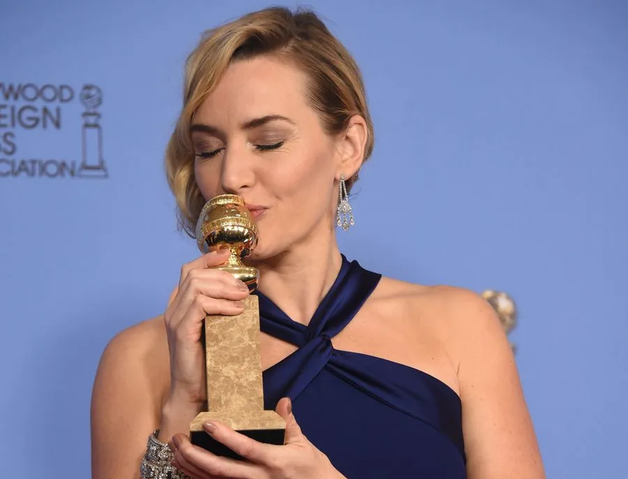 Kate Winslet saat ciumi piala Golden Globenya/©AFP