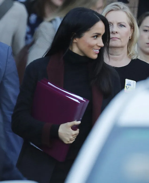 Meghan sembunyikan perutnya dengan bantuan dua rangkap map seperti ini © MEGA via dailymail.co.uk