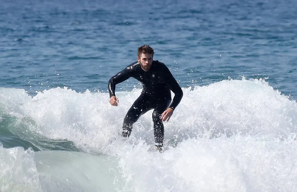 Liam asyik main selancar, sementara Miley memilih untuk berjemur © dailymail.co.uk