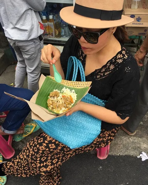 Dengan tas uniknya, Okky nikmati makanan pedagang kaki lima. Yummy! /©instagram.com/oq_lukman