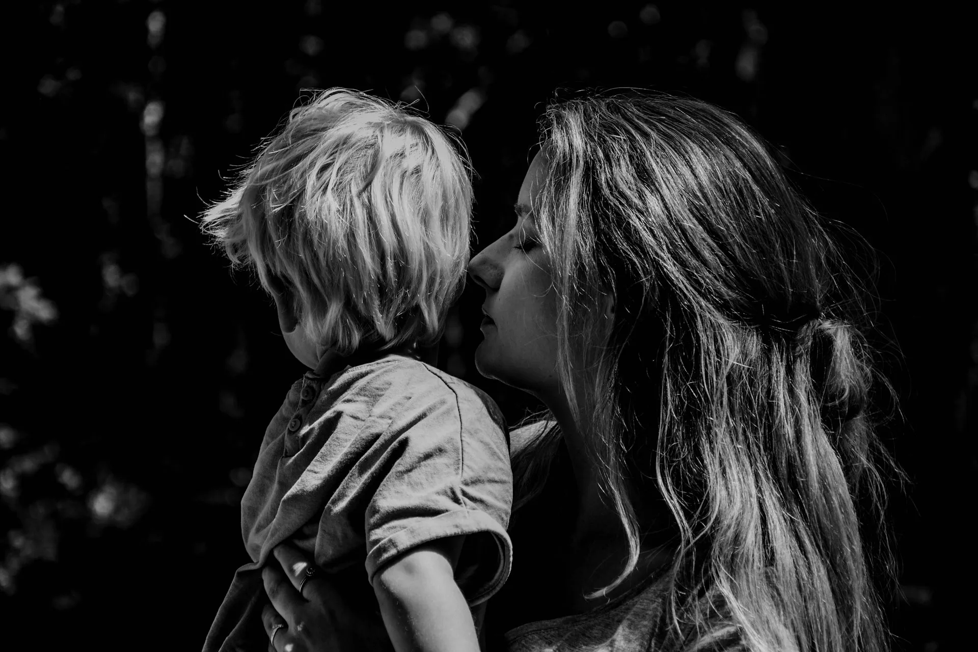Seorang wanita menggendong anak dan menciumnya (credit: Unsplash)