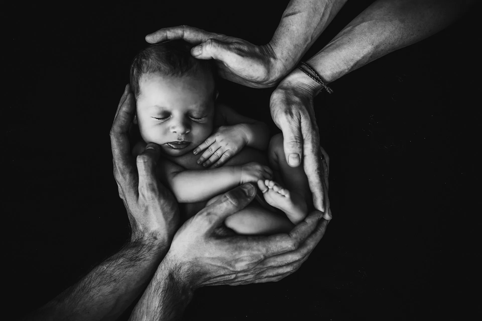 Dua tangan memeluk bayi laki-laki (credit: Unsplash)