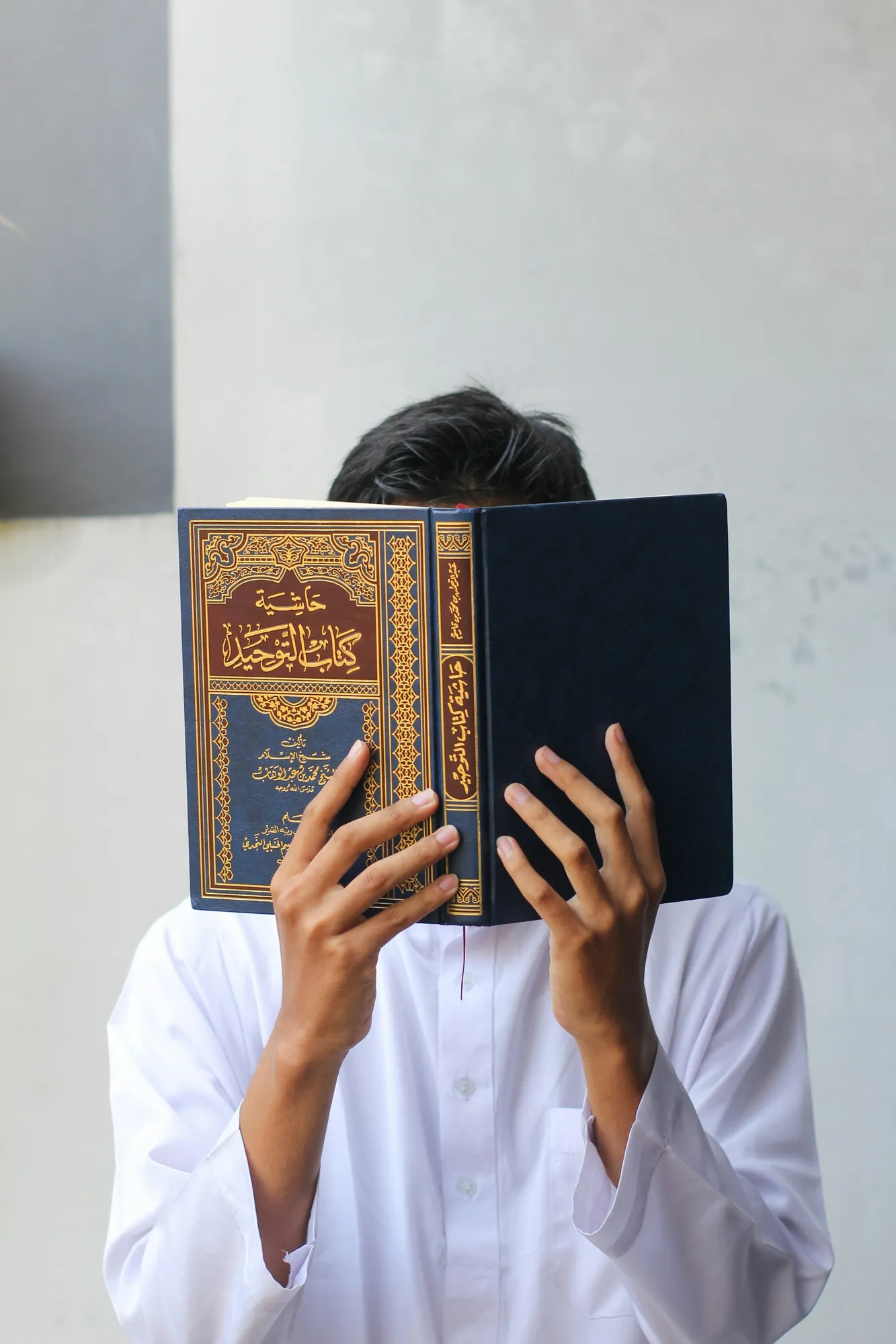 Seorang pria memegang kitab suci Al Quran (credit: unsplash)
