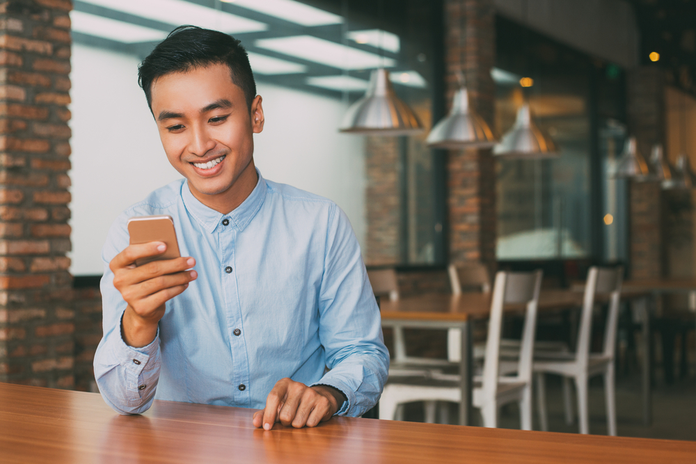 Illustration of a man holding a smartphone. (c) Shutterstock/Mangostar