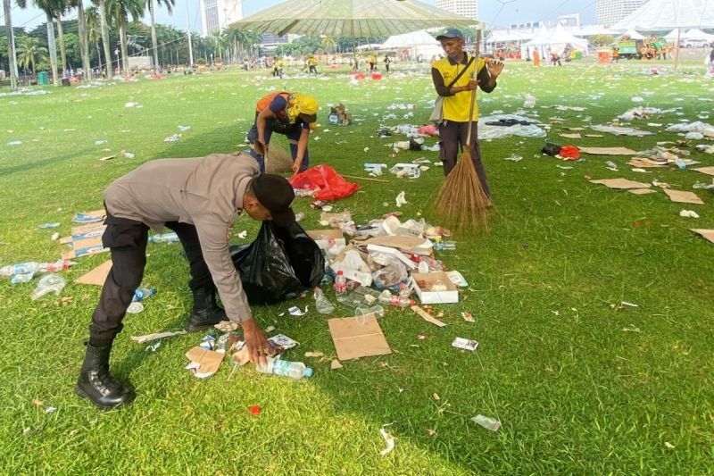 Polisi Bantu Bersihkan Sampah Usai May Day 2025 di Monas, Tunjukkan Sisi Humanis