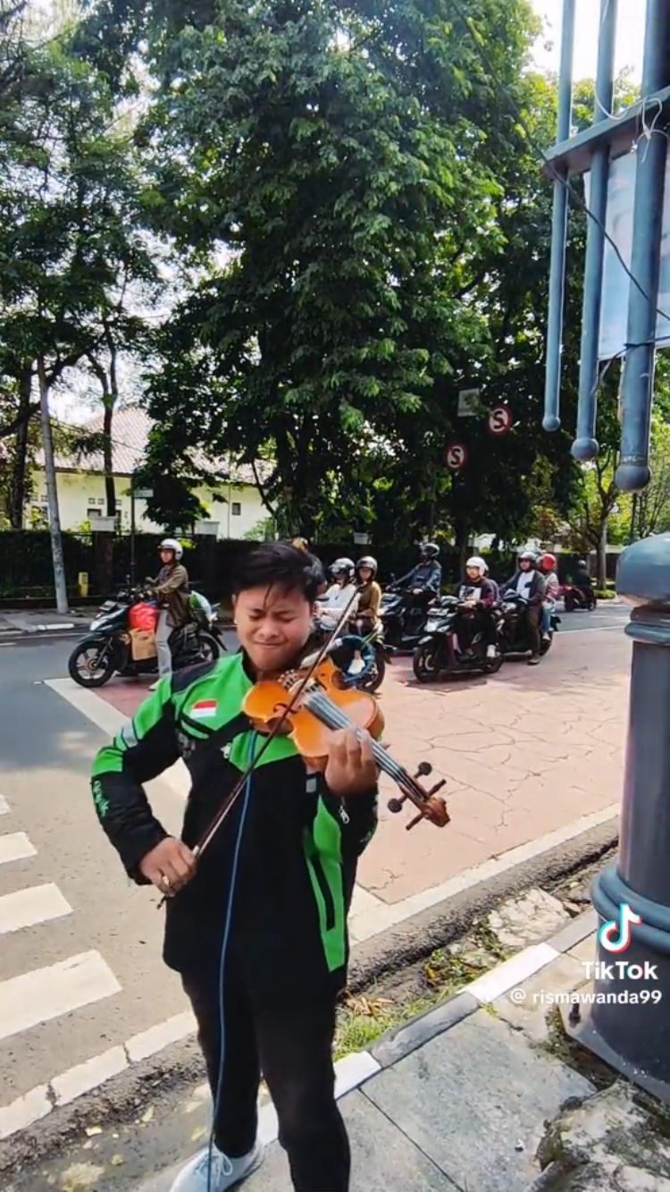 Aksi Pria Berjaket Ojol Main Biola di Lampu Merah Ini Viral, Keren Banget