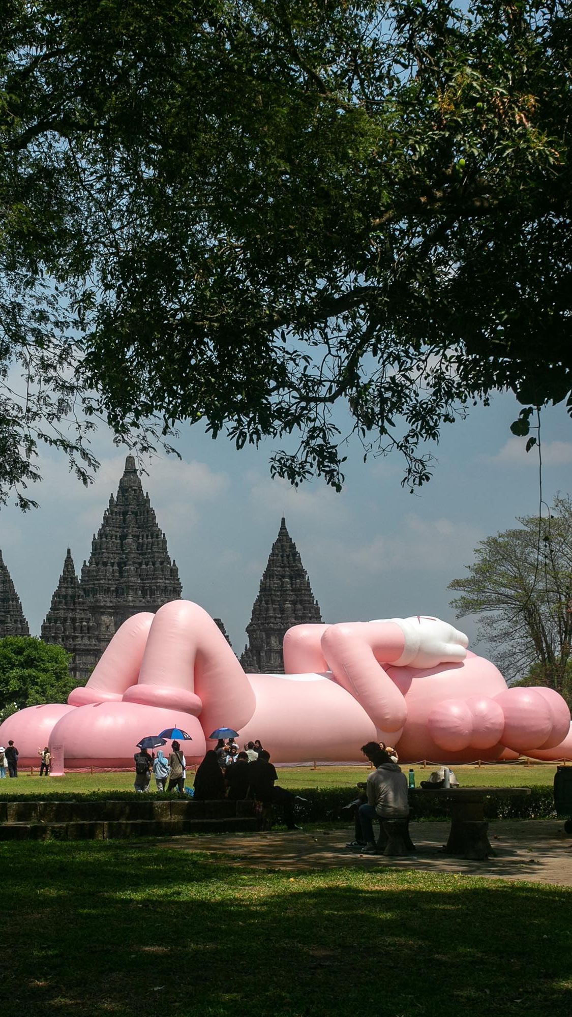 FOTO: Momen KAWS Liburan di Indonesia, Begini Potretnya Saat Asyik Rebahan di Candi Prambanan